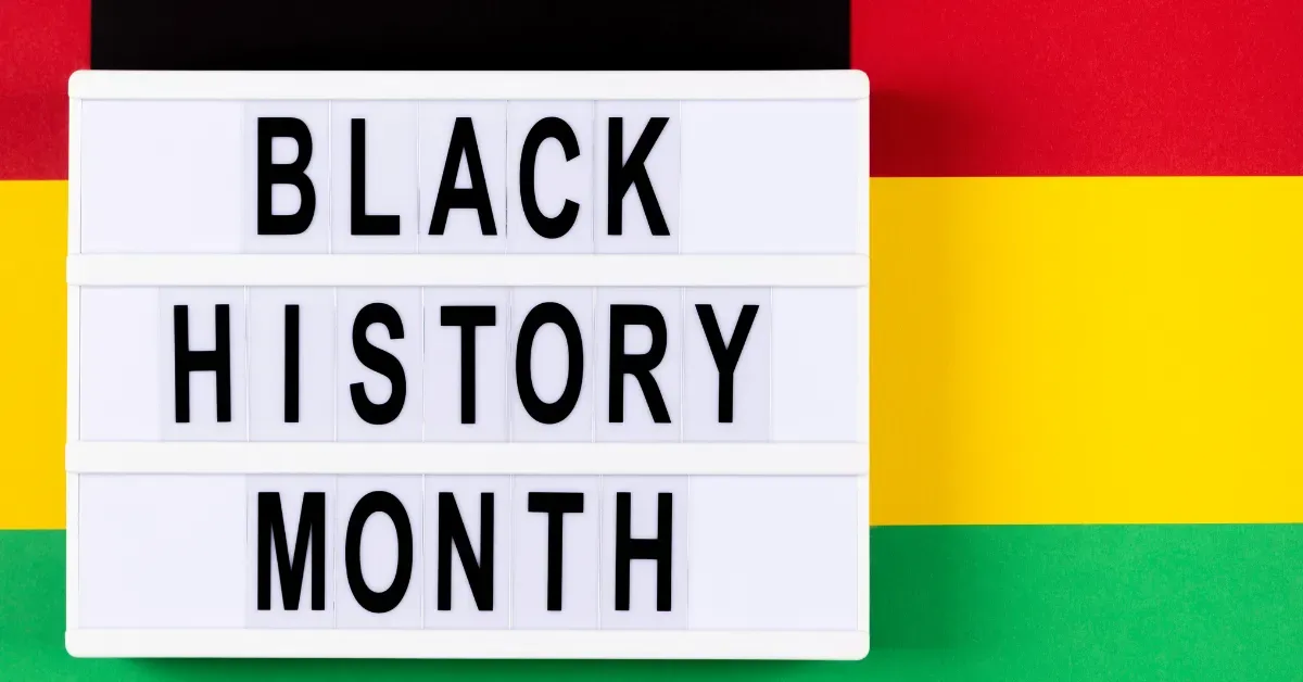 A white lightbox displaying the text "Black History Month" in black letters against a Pan-African flag background of red, black, yellow, and green.