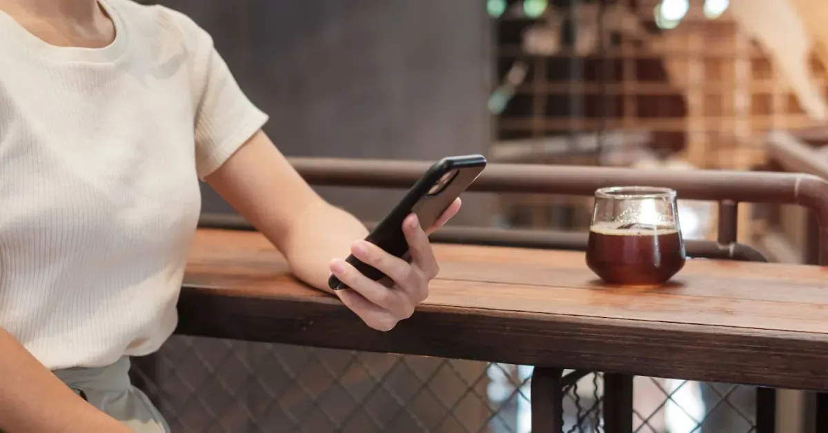 Woman holding a phone in a coffee shop.